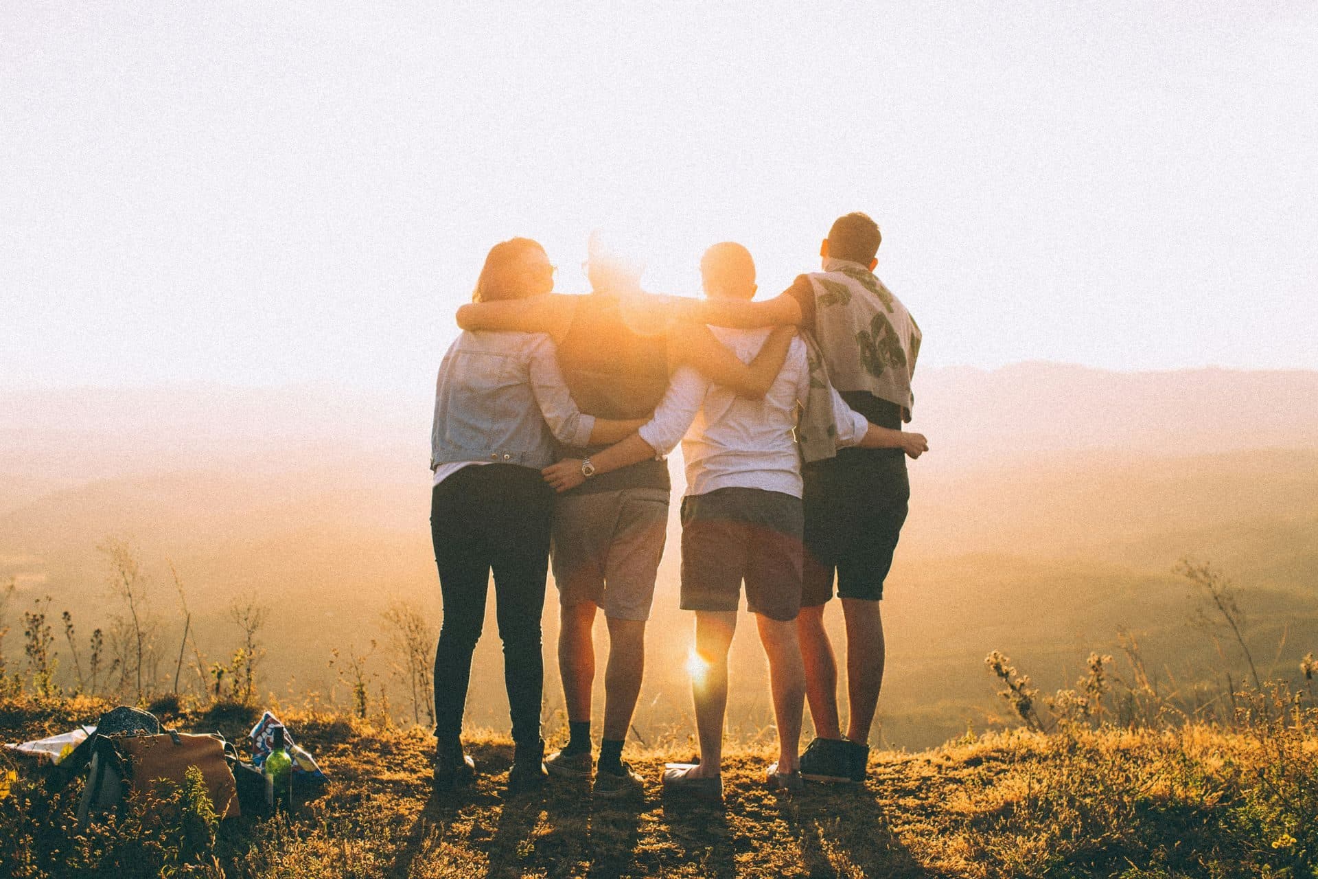 Friends standing arm in arm at sunset