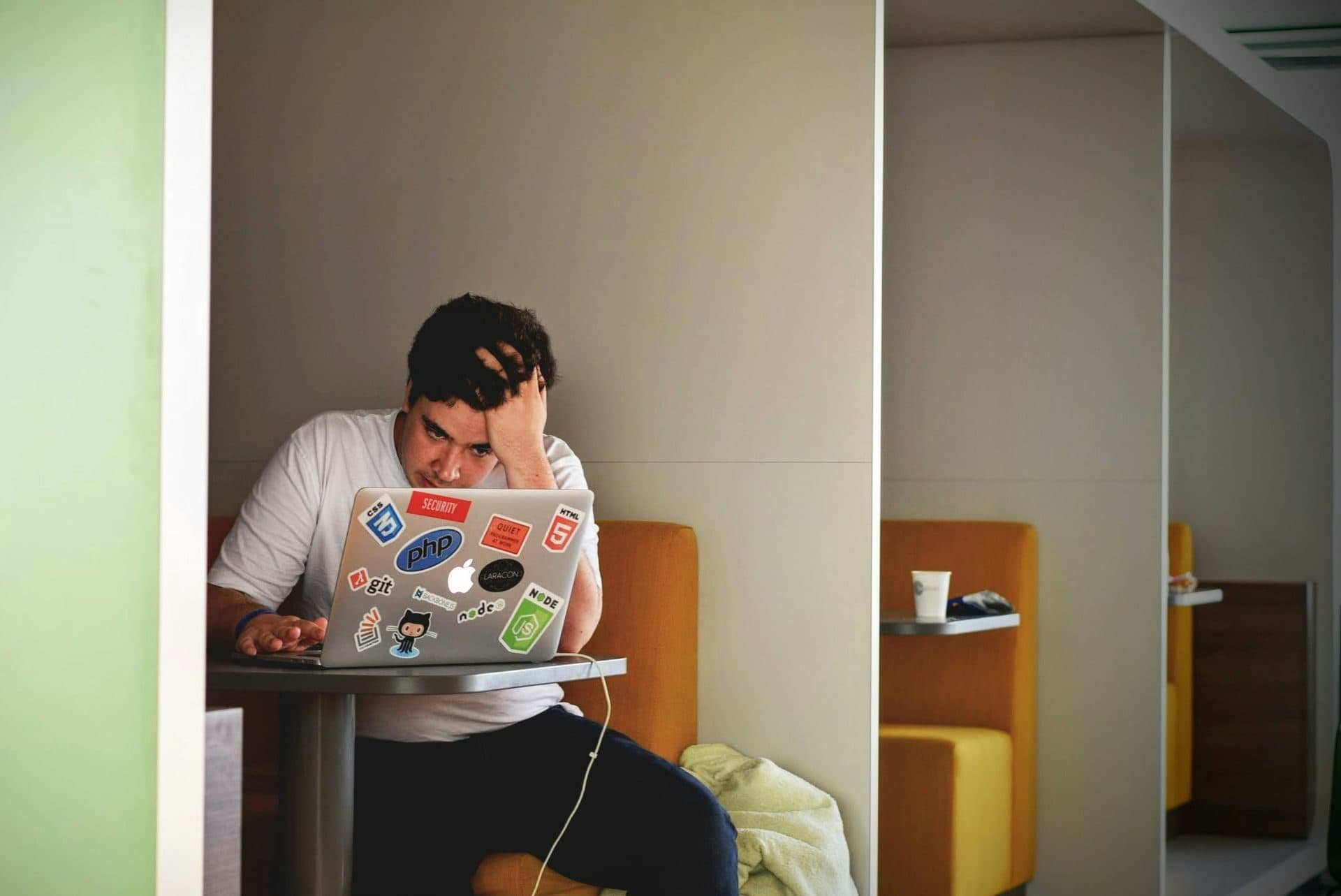 A man sitting at a laptop with his head in his hand, overwhelmed by work stress and burnout