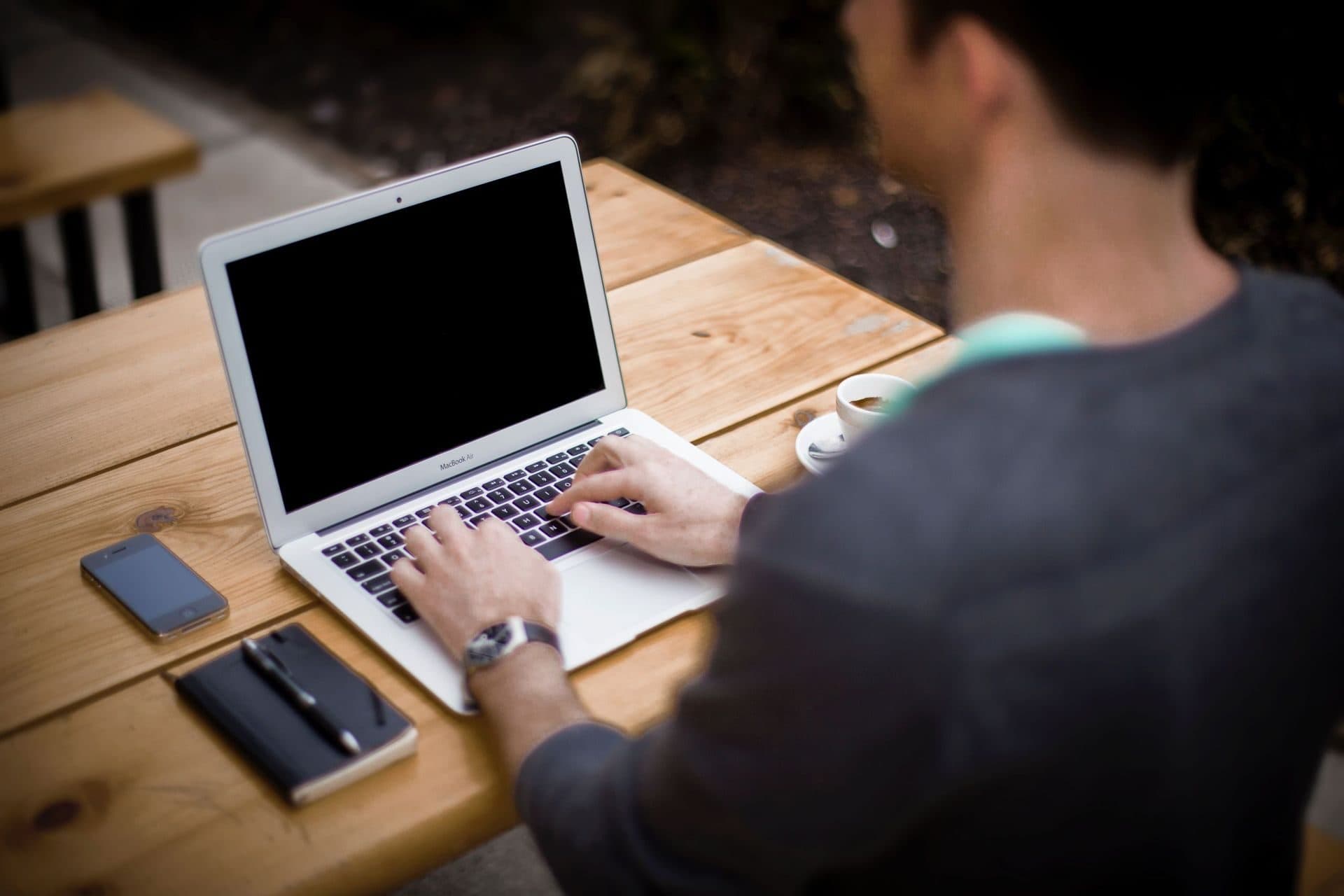 A man working thoughtfully at a laptop in a bright office